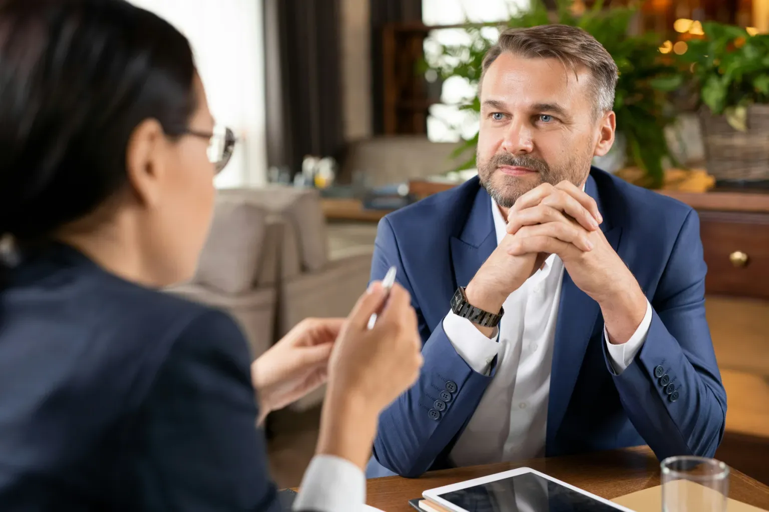 Man in a business suit listening to another person across a table