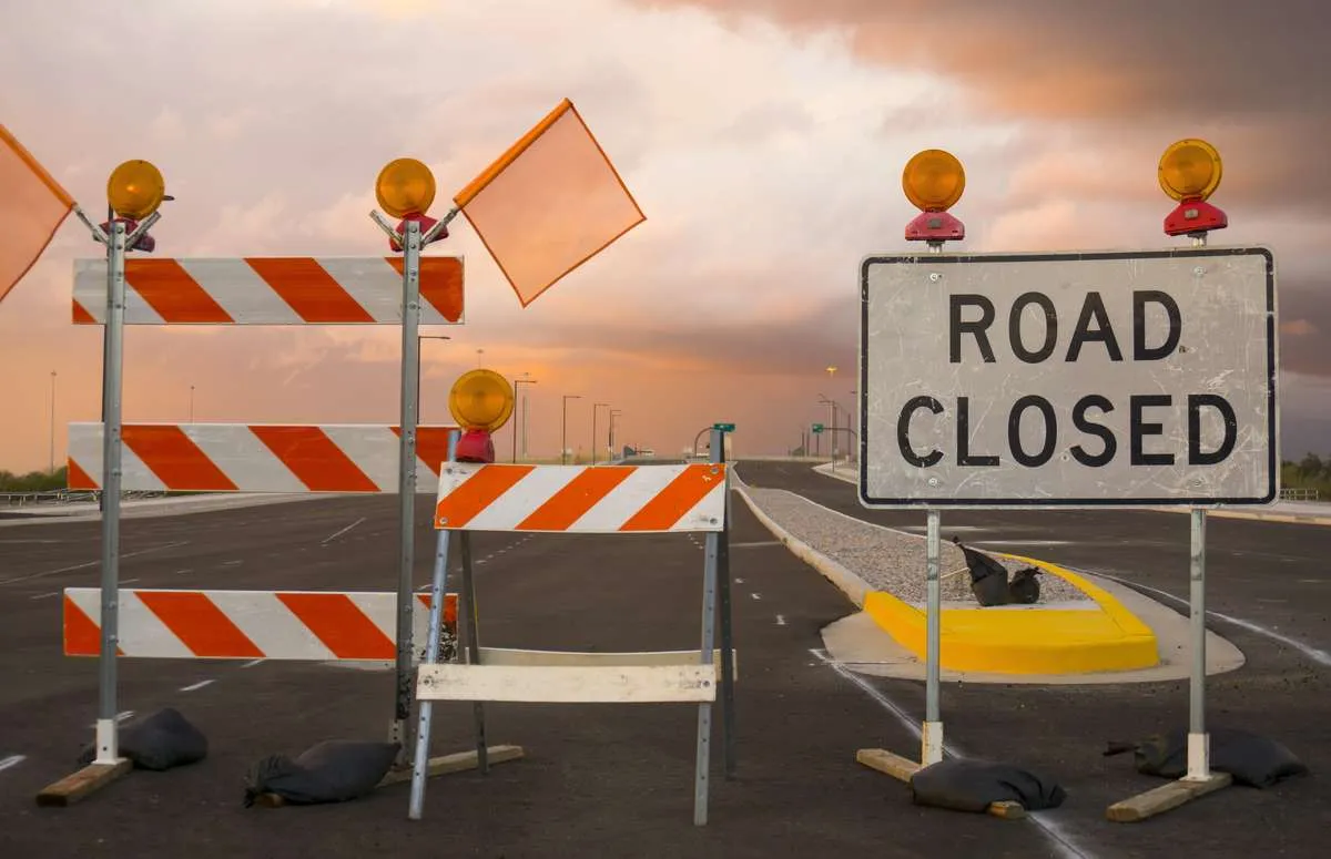 Road Closed sign and construction barriers blocking a roadway