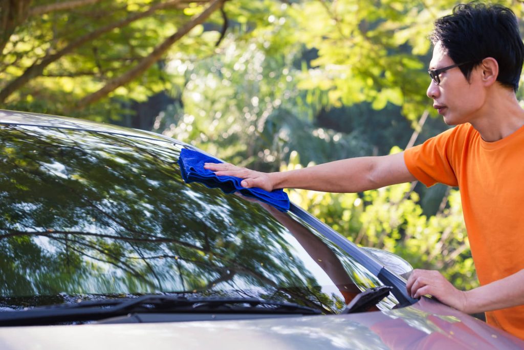 Car owner wiping down the windshield by hand