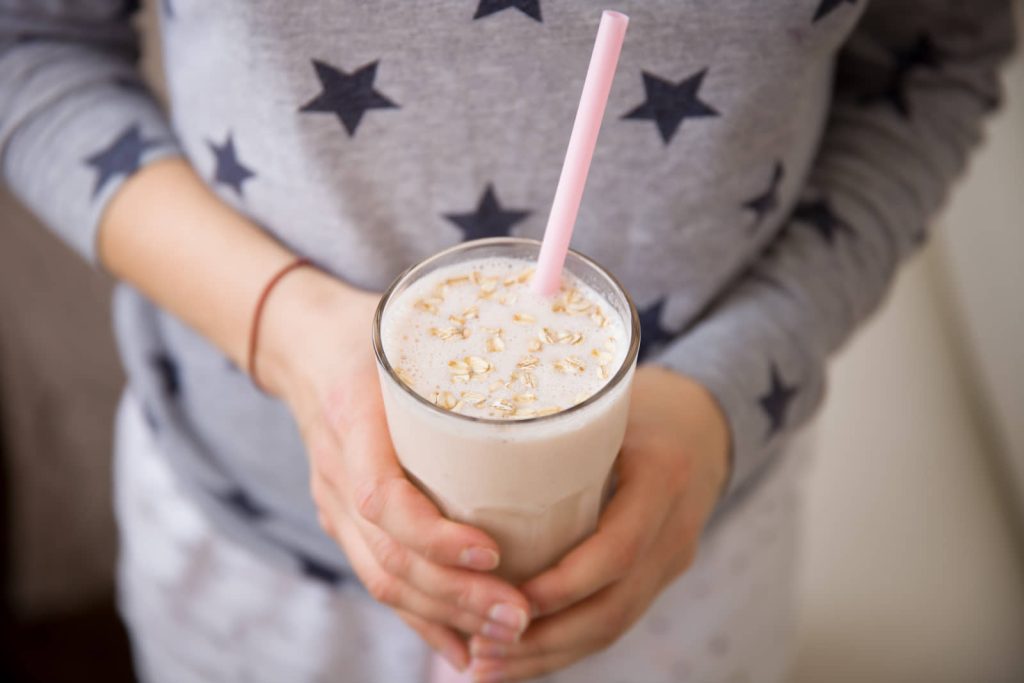 Person holding a creamy drink topped with oats