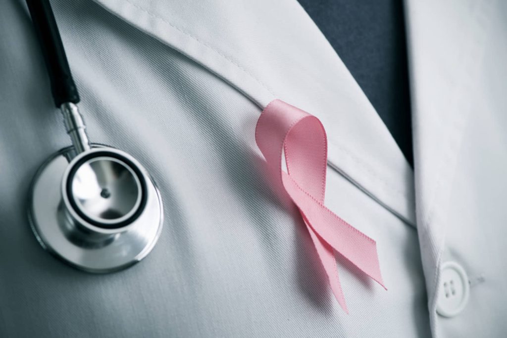 Pink awareness ribbon and stethoscope on a physician's white coat