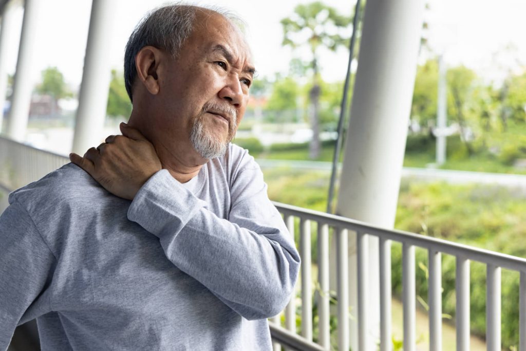 Older man holding his shoulder while living with chronic pain